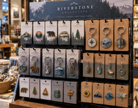 Expositor de tienda con pins, llaveros y charms metálicos esmaltados personalizados, presentados en cartulinas impresas para su
