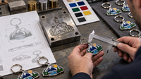 Fotografía del proceso de fabricación de un llavero metálico personalizado a medida, desde el diseño y el molde hasta la pieza t Fotografía del proceso de fabricación de un llavero metálico personalizado a medida, desde el diseño y el molde hasta la pieza t
