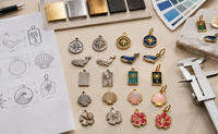 Diferentes fases del proceso de fabricación de charms metálicos personalizados sobre mesa de trabajo Diferentes fases del proceso de fabricación de charms metálicos personalizados sobre mesa de trabajo